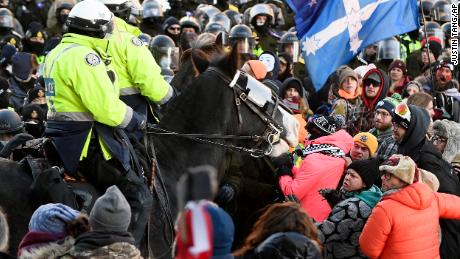 Des policiers à cheval tentent de disperser des manifestants à Ottawa vendredi.