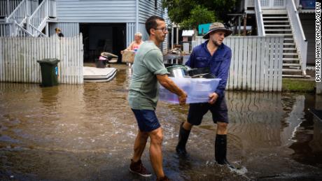 Des résidents transportent des effets personnels alors qu’ils nettoient leurs maisons dans la banlieue endommagée par les inondations de Newmarket à Brisbane le 1er mars 2022. 