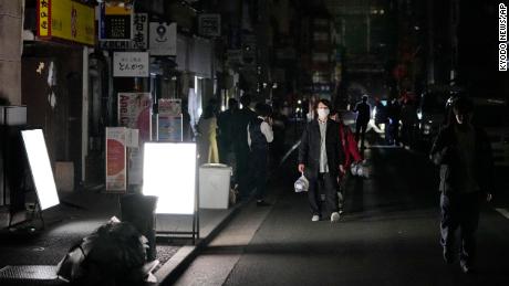 Des gens marchent dans une rue lors d’une panne d’électricité à Tokyo.