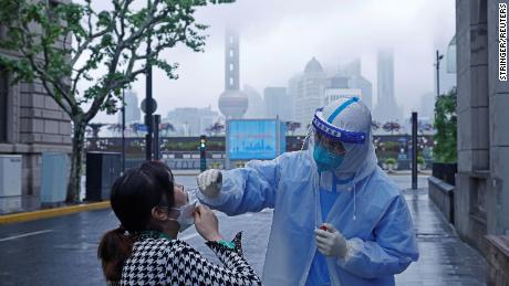 Un travailleur médical en tenue de protection prélève un échantillon d’écouvillon d’un résident de Shanghai le 26 avril 2022.