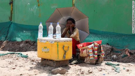 Une fille qui vend de l’eau utilise un parapluie pour se protéger du soleil alors qu’elle attend des clients à New Delhi, en Inde, le 27 avril.