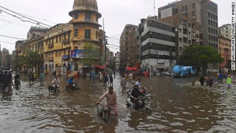 Des gens pataugent dans une rue inondée après de fortes pluies de mousson à Karachi le 25 juillet.