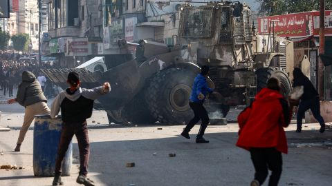 Des Palestiniens lancent des pierres sur un bulldozer de l’armée israélienne lors d’un raid dans la ville de Jénine en Cisjordanie occupée, le 26 janvier 2023. 
