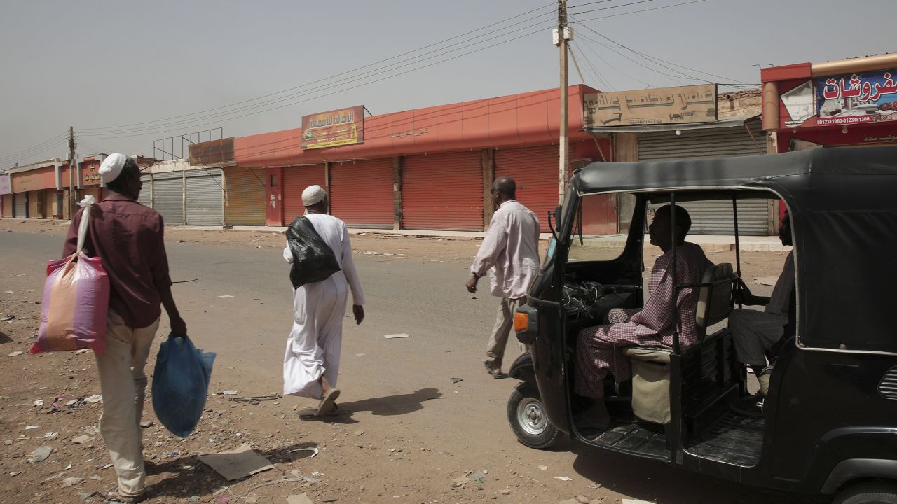 Des gens passent devant des magasins fermés à Khartoum, au Soudan, le lundi 17 avril 2023.