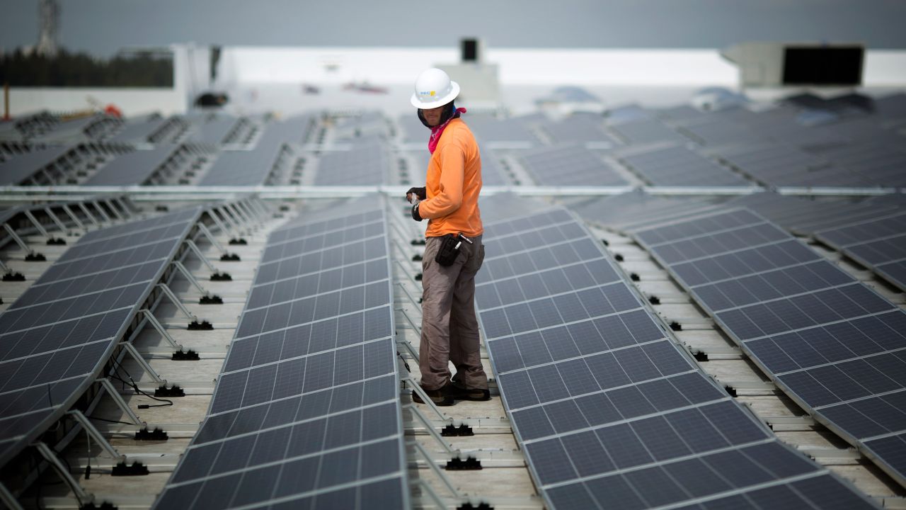 Un ouvrier marche parmi les panneaux solaires installés sur le toit d’un IKEA à Miami en 2014. En février, IKEA avait installé des installations solaires dans 90% de ses sites américains.